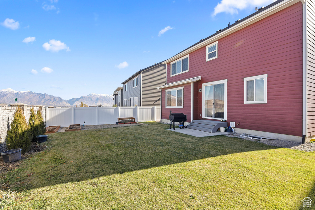 Back of property featuring a mountain view and a lawn