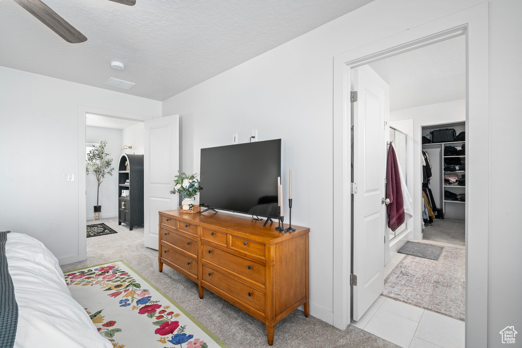 Carpeted bedroom with ceiling fan, a closet, a spacious closet, and a textured ceiling