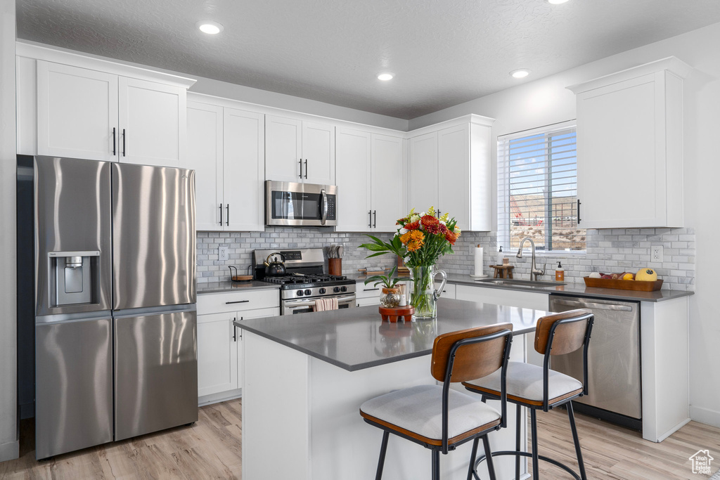 Kitchen featuring white cabinets, a center island, stainless steel appliances, and sink