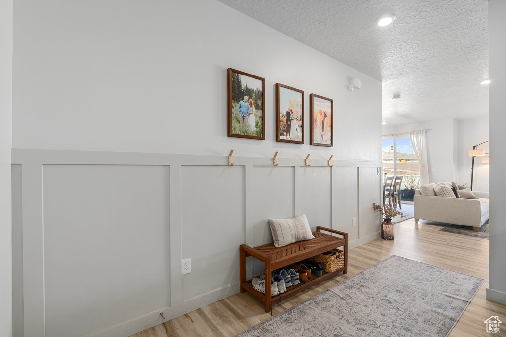 Hallway with a textured ceiling and light hardwood / wood-style floors