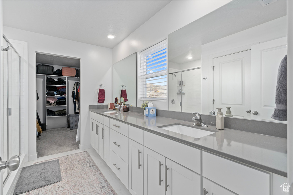 Bathroom featuring tile patterned floors, vanity, and a shower with door