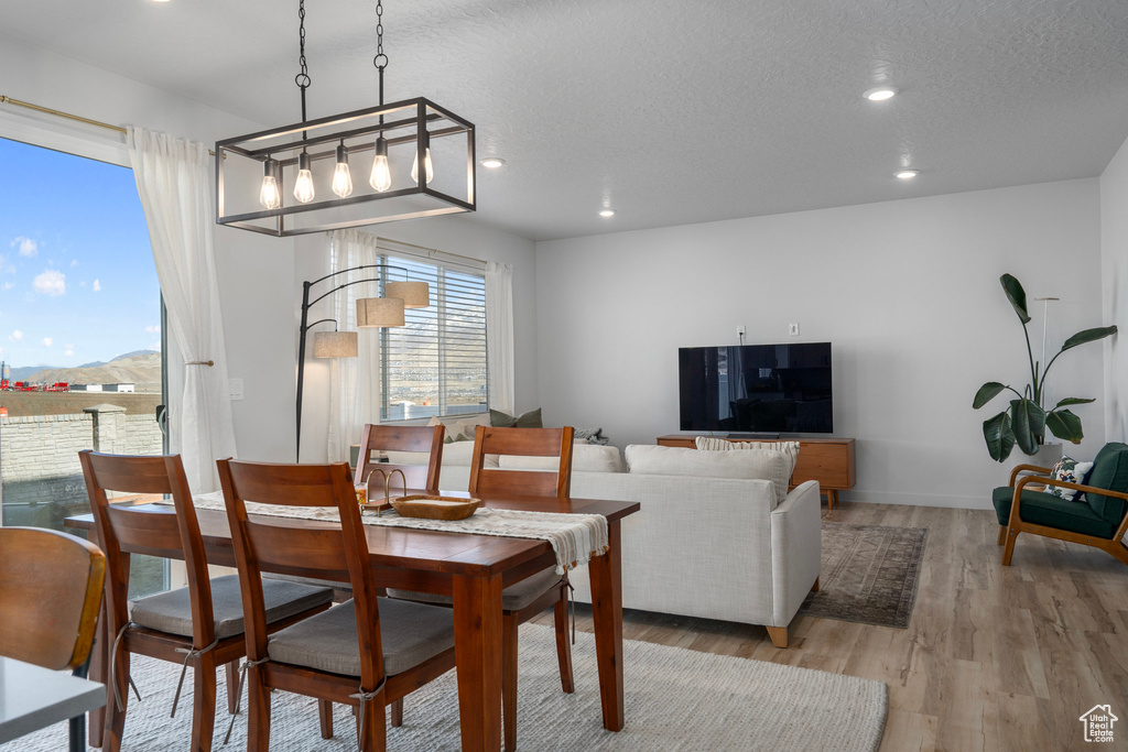 Dining room with a mountain view, light wood-type flooring, and a textured ceiling