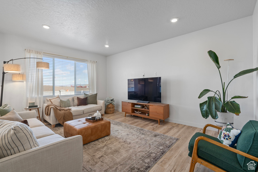 Living room featuring light wood-type flooring and a textured ceiling