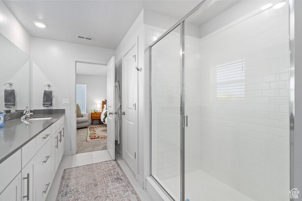 Bathroom featuring tile patterned floors, a shower with door, and vanity