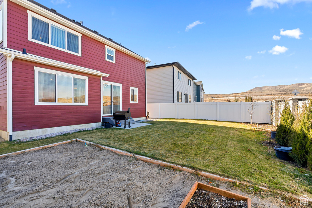 Back of property featuring a lawn, a mountain view, and a patio