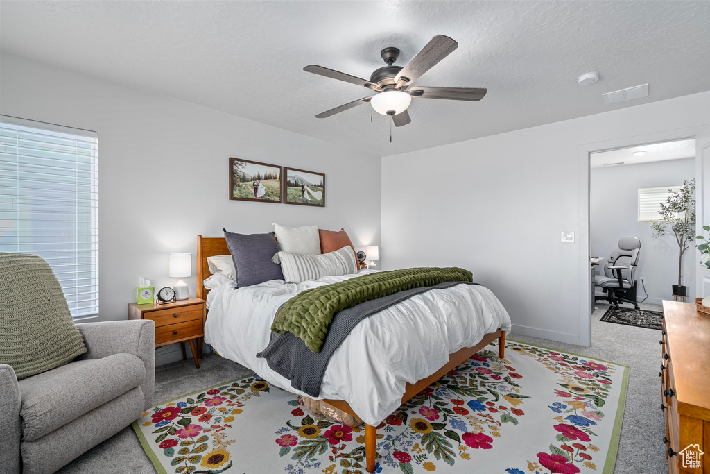 Carpeted bedroom featuring ceiling fan and a textured ceiling