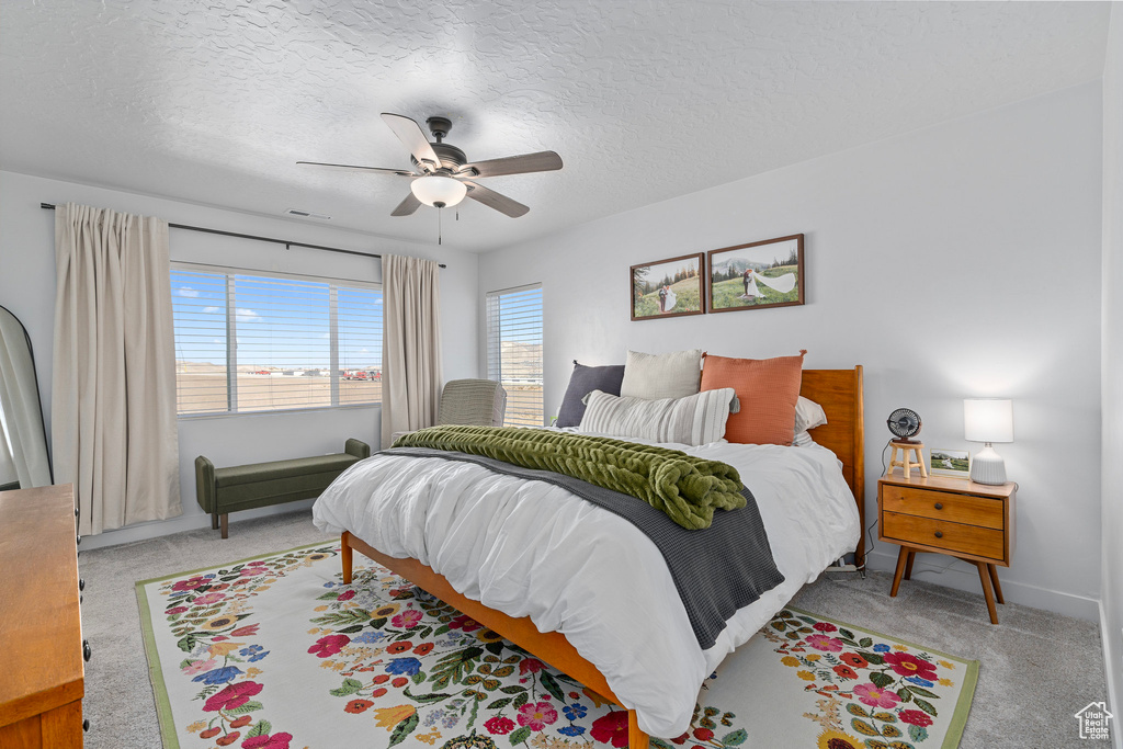 Carpeted bedroom featuring ceiling fan and a textured ceiling