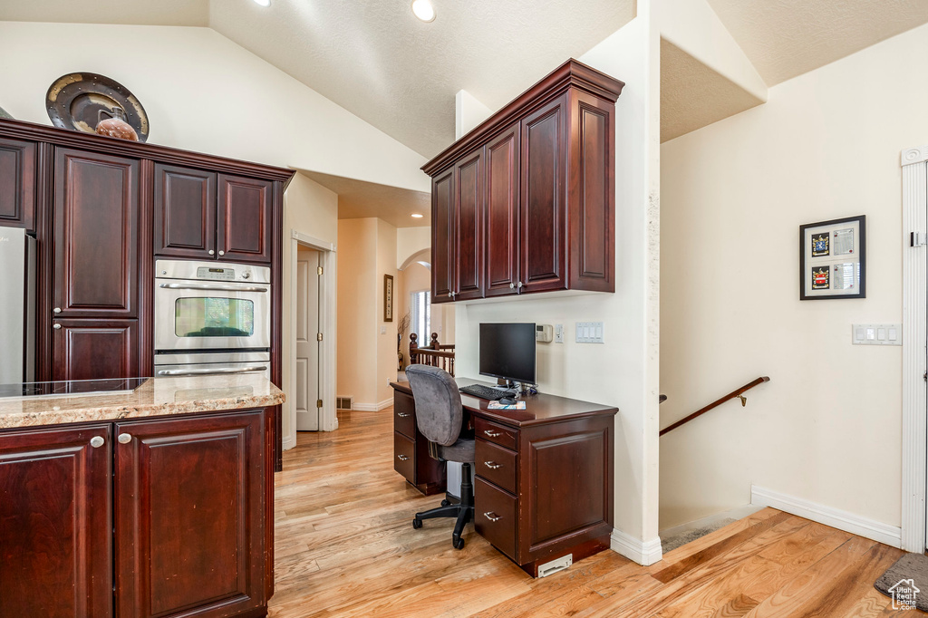 Office space featuring vaulted ceiling and light wood-type flooring