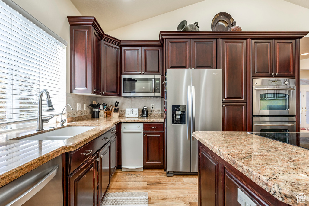 Kitchen featuring appliances with stainless steel finishes, light hardwood / wood-style floors, a wealth of natural light, and lofted ceiling