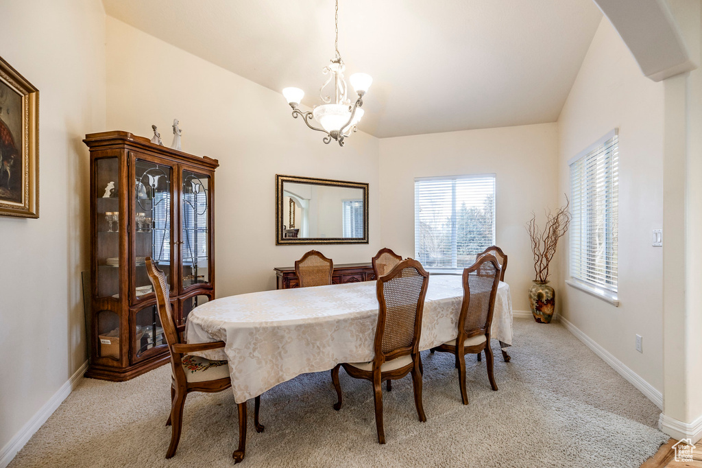 Carpeted dining space featuring a notable chandelier and vaulted ceiling