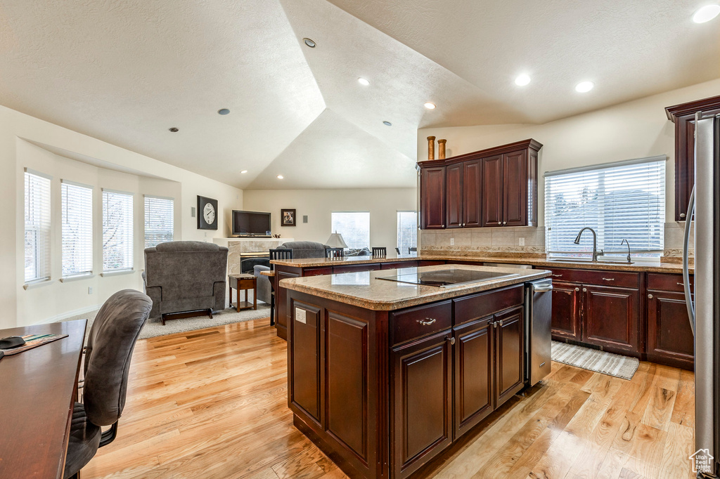 Kitchen with a center island, sink, light hardwood / wood-style floors, lofted ceiling, and black electric cooktop