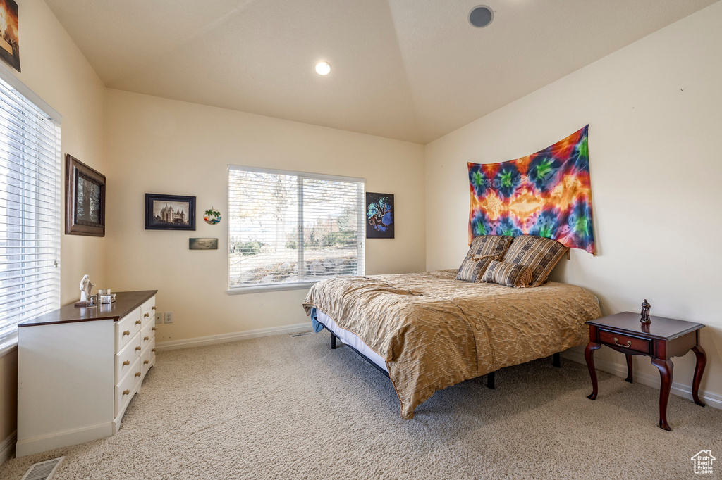 Bedroom featuring vaulted ceiling, light carpet, and multiple windows