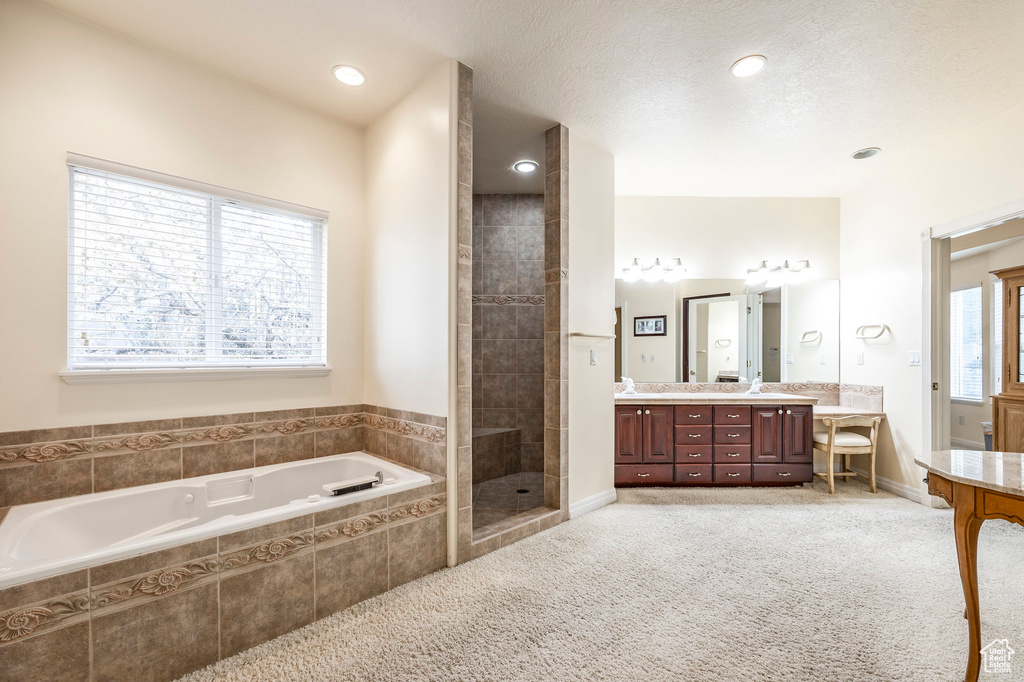 Bathroom with a textured ceiling, vanity, and separate shower and tub