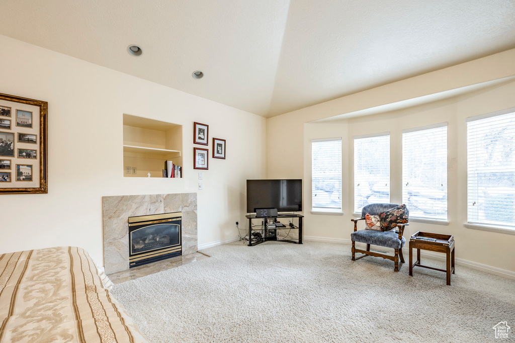 Living room with carpet flooring, a wealth of natural light, a premium fireplace, and vaulted ceiling