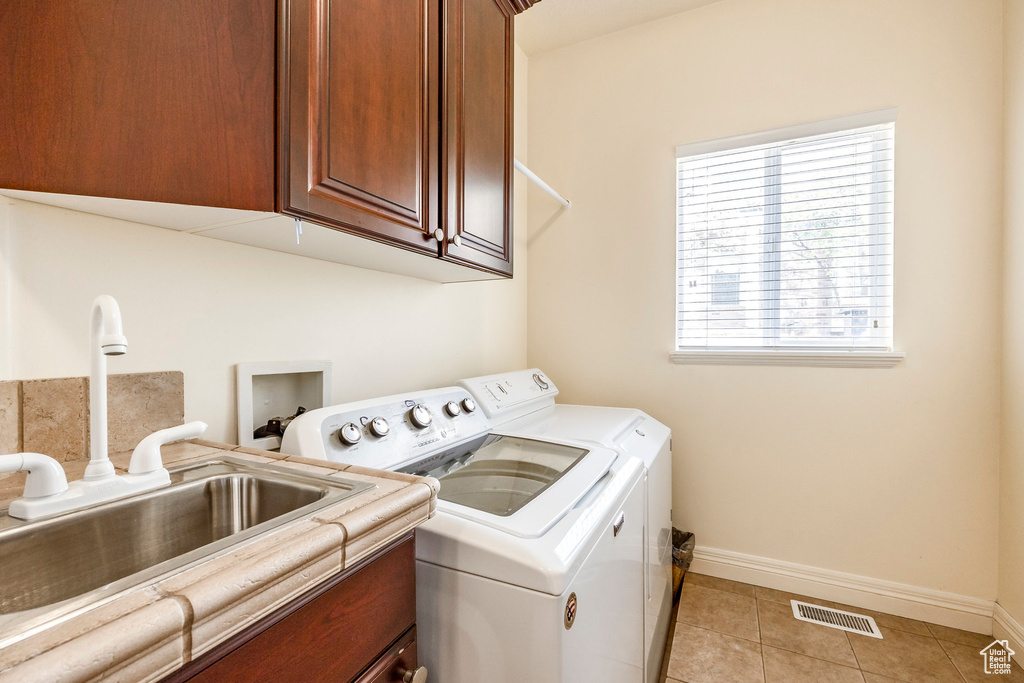 Washroom featuring cabinets, independent washer and dryer, sink, and light tile patterned floors