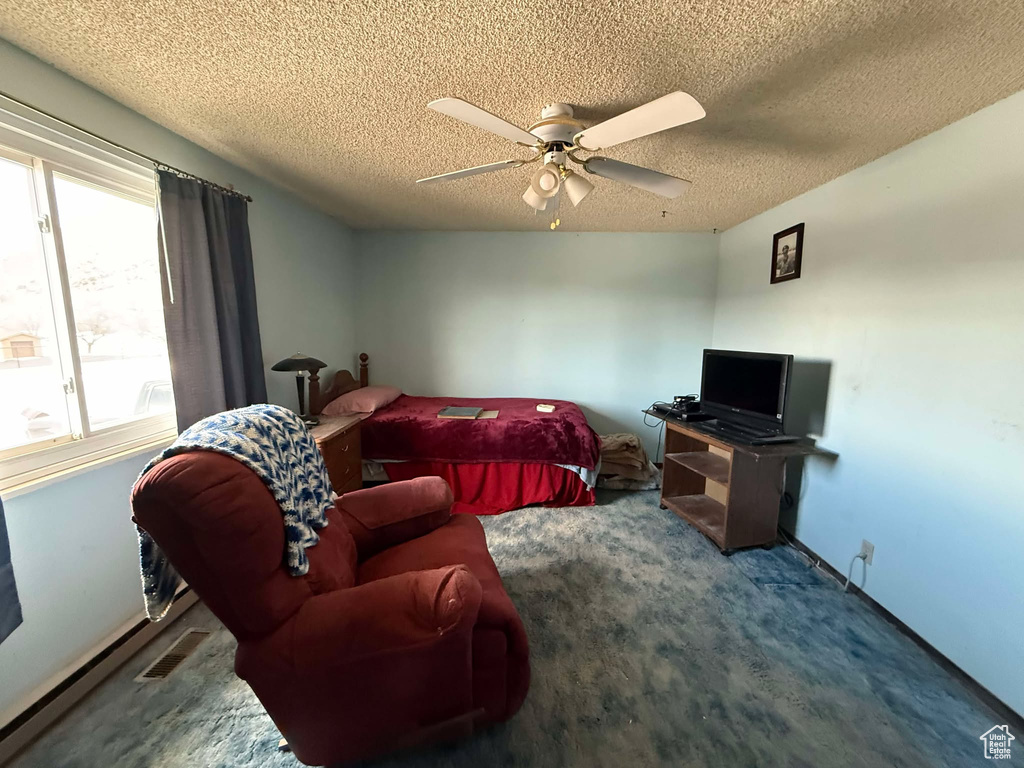 Carpeted bedroom featuring ceiling fan and a textured ceiling