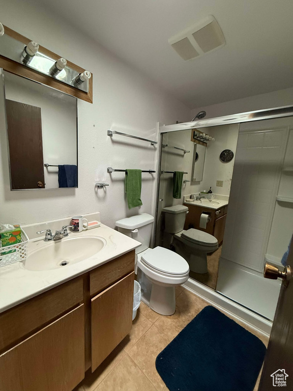 Bathroom with vanity, toilet, a shower with shower door, and tile patterned flooring