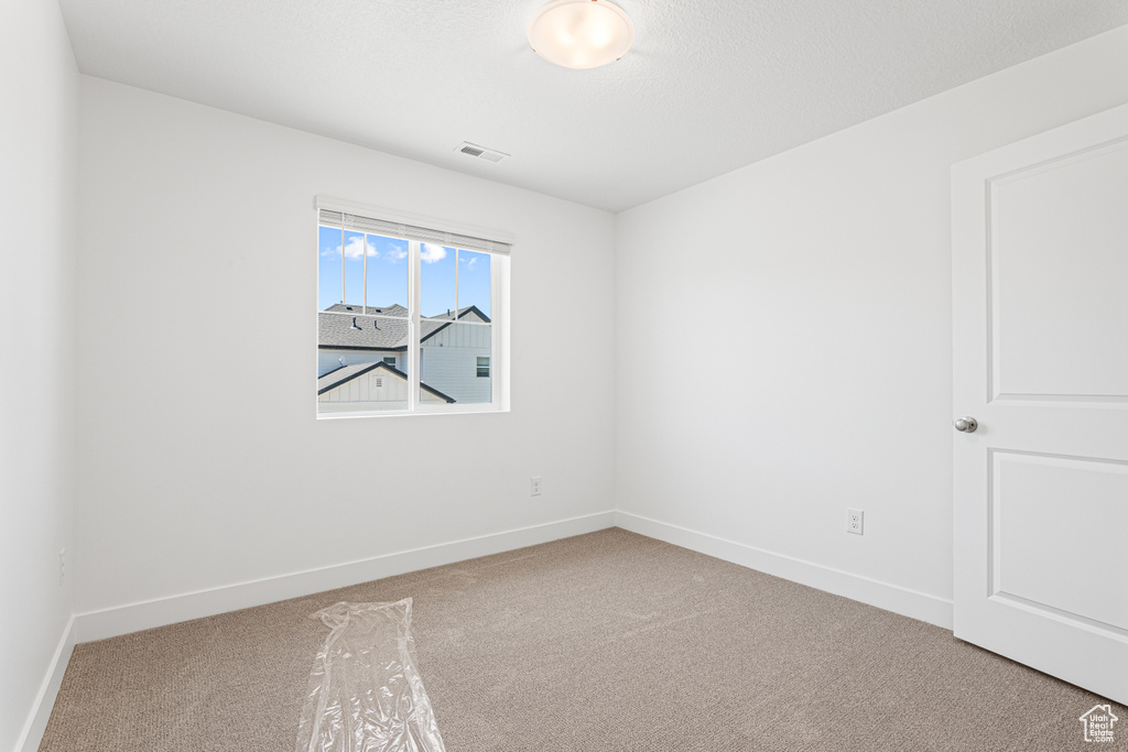 Carpeted spare room featuring baseboards
