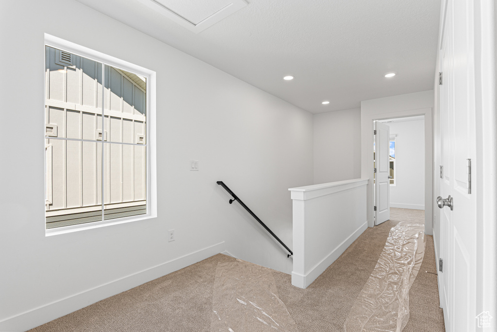 Hall with an upstairs landing, carpet, and recessed lighting