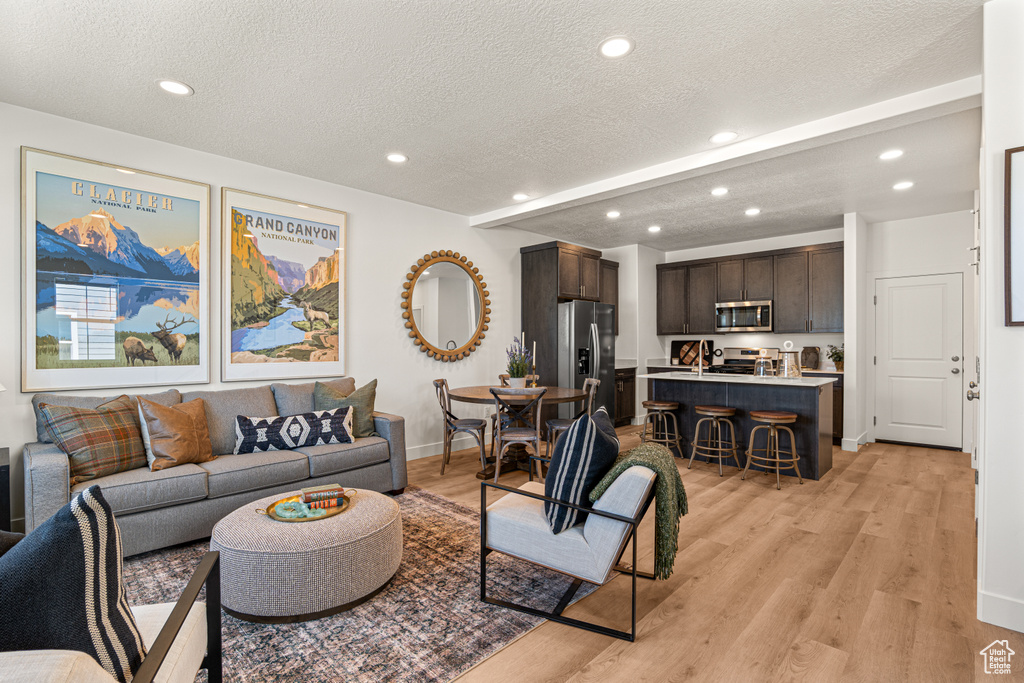 Living area featuring recessed lighting, light wood-style flooring, and a textured ceiling