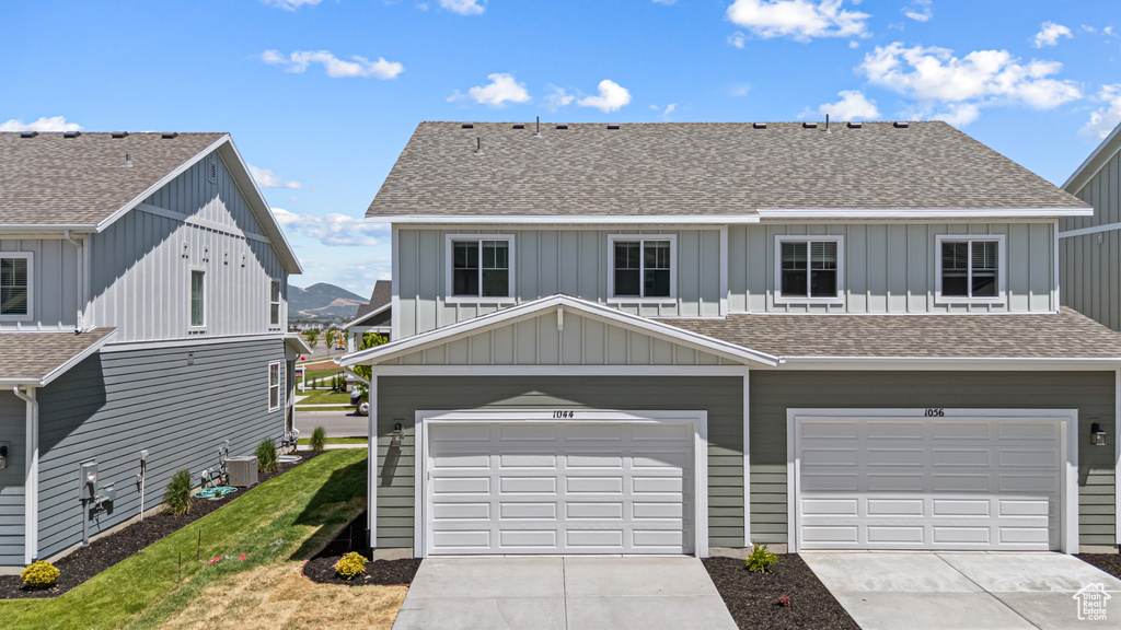 View of front facade with board and batten siding, roof with shingles, and concrete driveway