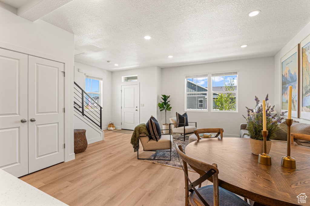 Dining room featuring a textured ceiling, stairway, light wood-style flooring, recessed lighting, and plenty of natural light