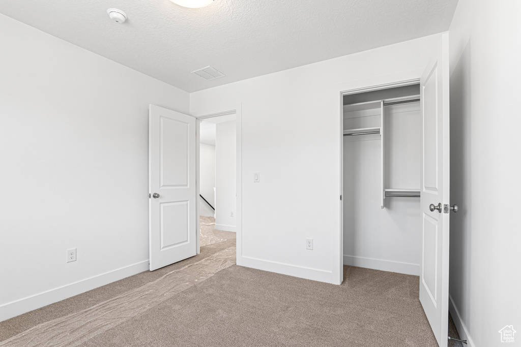 Unfurnished bedroom featuring carpet floors, a closet, and a textured ceiling