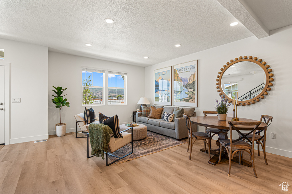 Living room featuring light wood-style floors, a textured ceiling, and recessed lighting