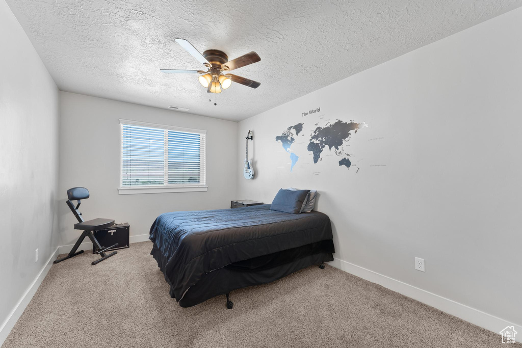 Bedroom featuring a textured ceiling, light colored carpet, and ceiling fan