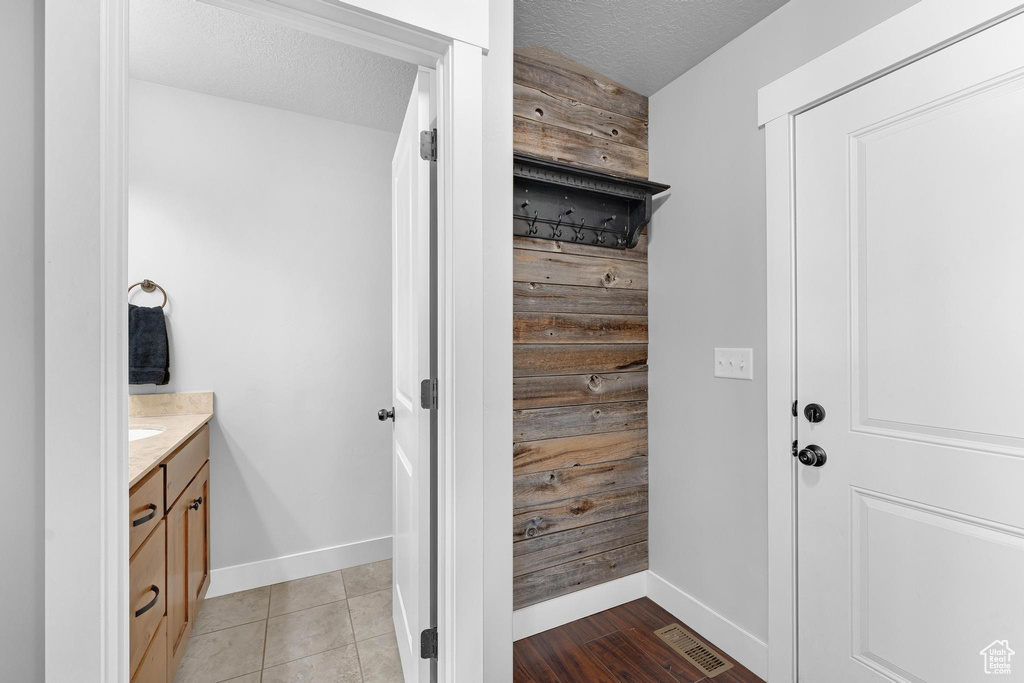 Bathroom featuring wood walls, vanity, wood-type flooring, and a textured ceiling