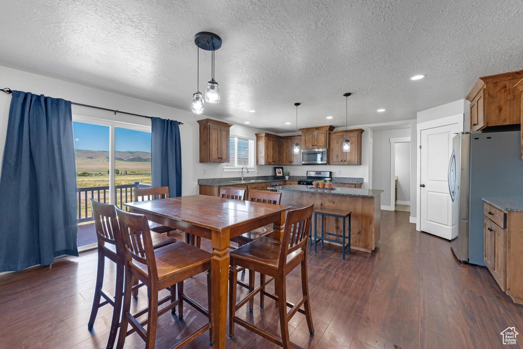 Dining area with a textured ceiling and dark hardwood / wood-style flooring