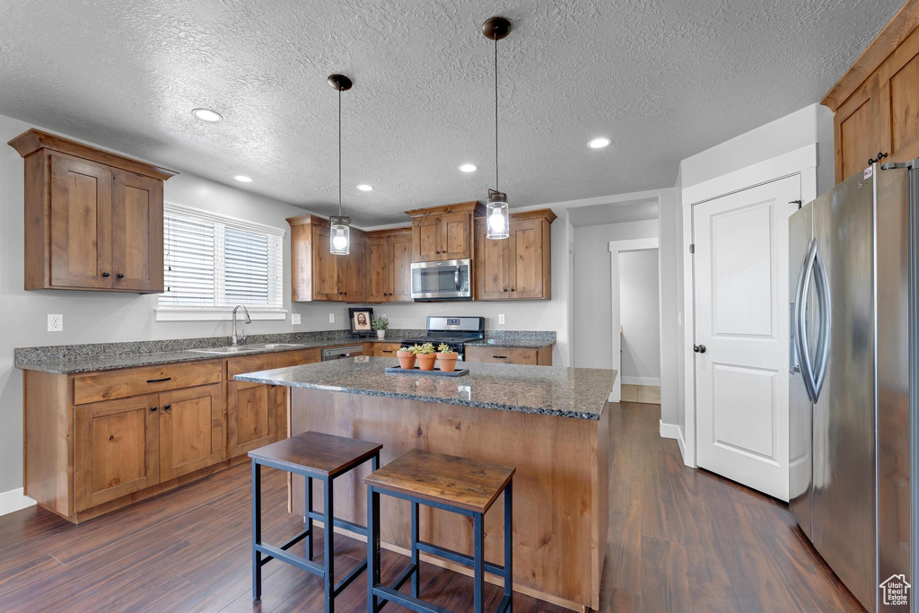 Kitchen featuring pendant lighting, dark hardwood / wood-style floors, a kitchen breakfast bar, and stainless steel appliances