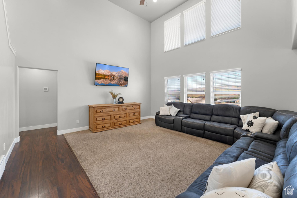 Living room with a high ceiling, dark hardwood / wood-style flooring, and ceiling fan