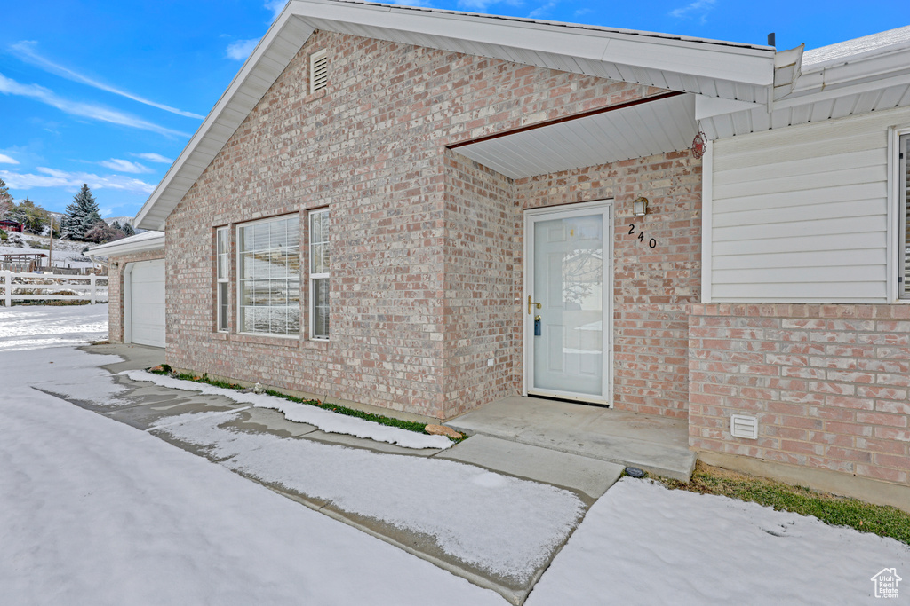 Snow covered property entrance with a garage