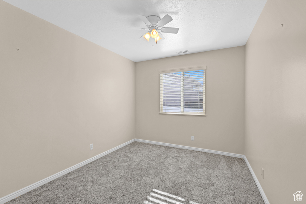Carpeted empty room featuring ceiling fan