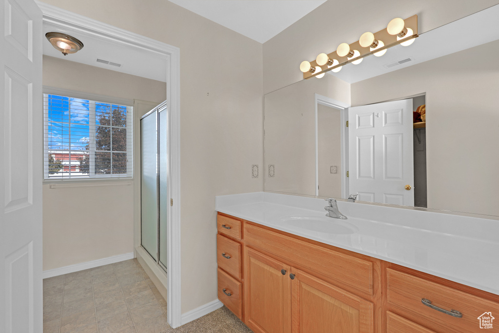 Bathroom featuring tile patterned flooring, vanity, and a shower with shower door
