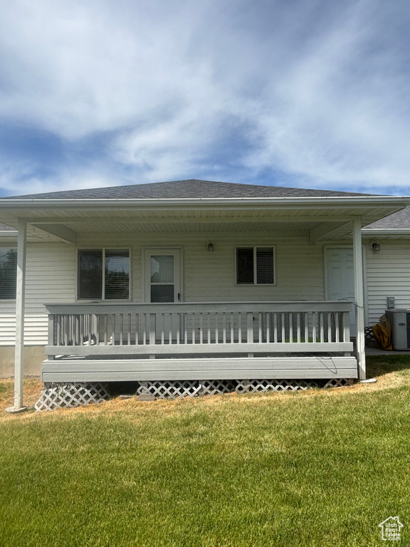View of front of house with a front yard, central AC unit, a porch, and a shingled roof