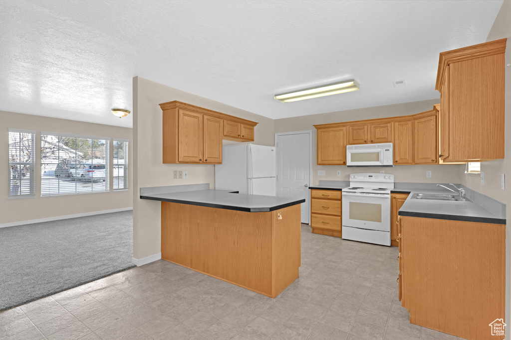 Kitchen with kitchen peninsula, a textured ceiling, white appliances, light colored carpet, and sink