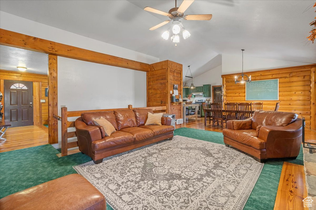 Living room with ceiling fan, wooden walls, vaulted ceiling, and hardwood / wood-style flooring
