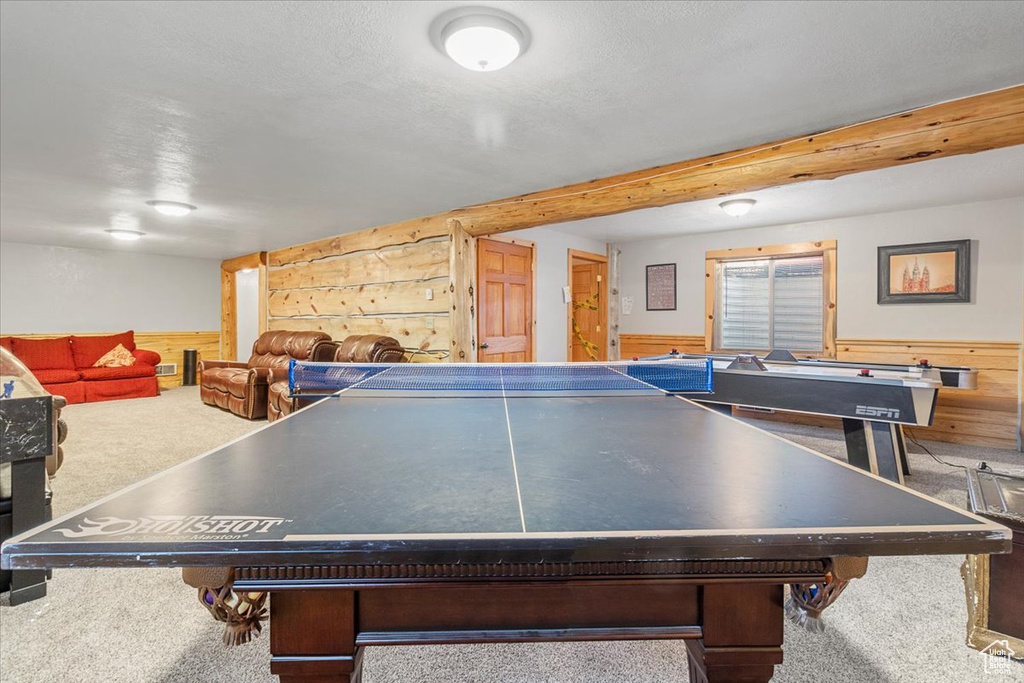 Game room featuring a textured ceiling, carpet floors, and wooden walls