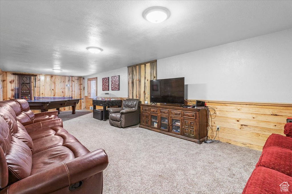Carpeted living room featuring a textured ceiling, pool table, and wood walls
