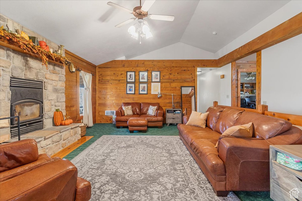 Carpeted living room with wood walls, a fireplace, ceiling fan, and vaulted ceiling