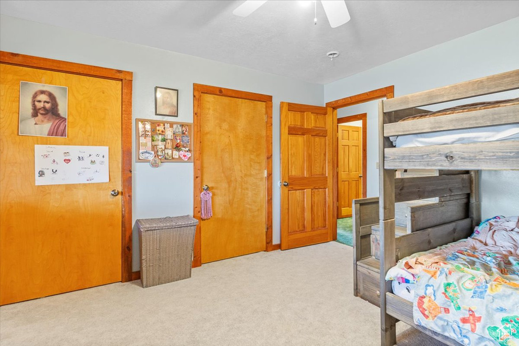 Carpeted bedroom with ceiling fan and a closet