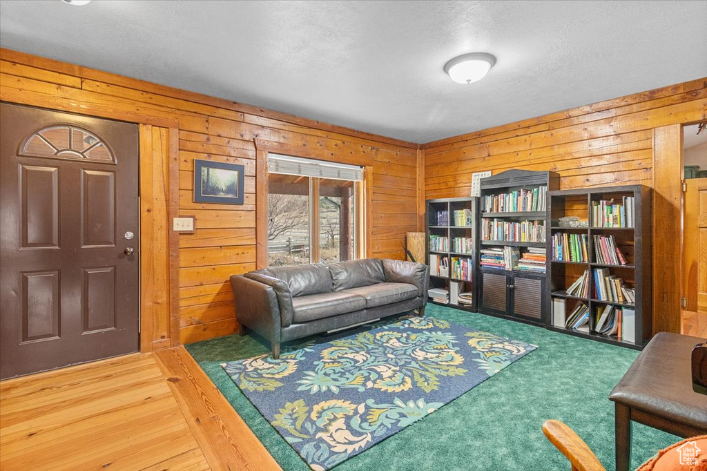 Living room with wooden walls, wood-type flooring, and a textured ceiling