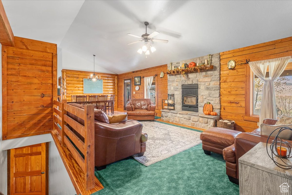 Carpeted living room with wood walls, ceiling fan, and vaulted ceiling