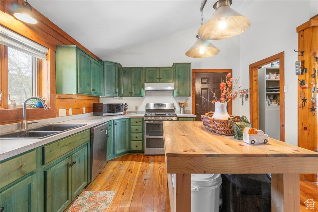 Kitchen with pendant lighting, green cabinets, sink, light hardwood / wood-style flooring, and stainless steel appliances
