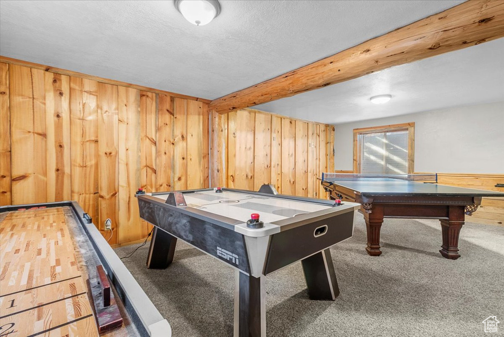 Game room featuring carpet, beam ceiling, a textured ceiling, and wooden walls