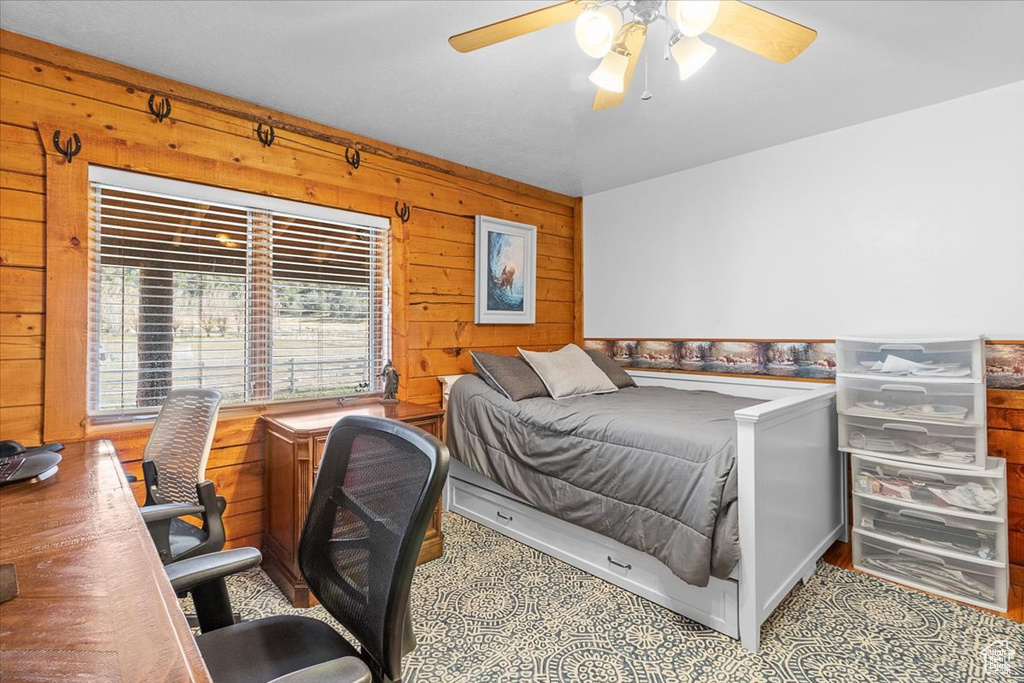 Bedroom with ceiling fan and wood walls