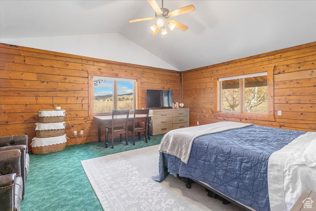 Carpeted bedroom with ceiling fan, wood walls, and vaulted ceiling
