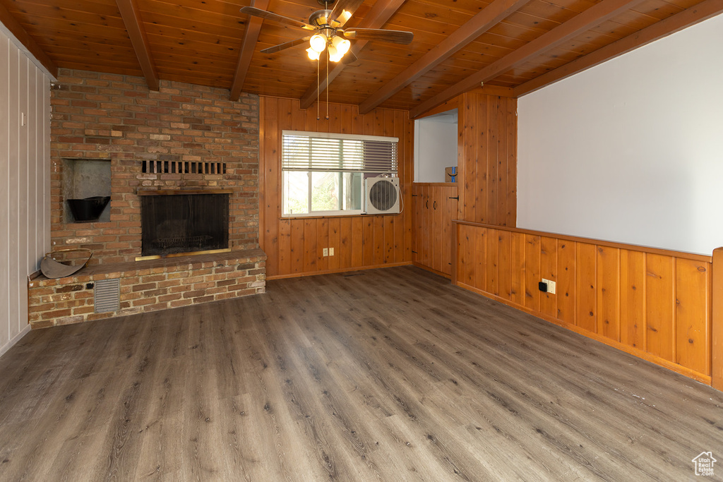 Unfurnished living room featuring wooden ceiling, beamed ceiling, wood-type flooring, and wood walls